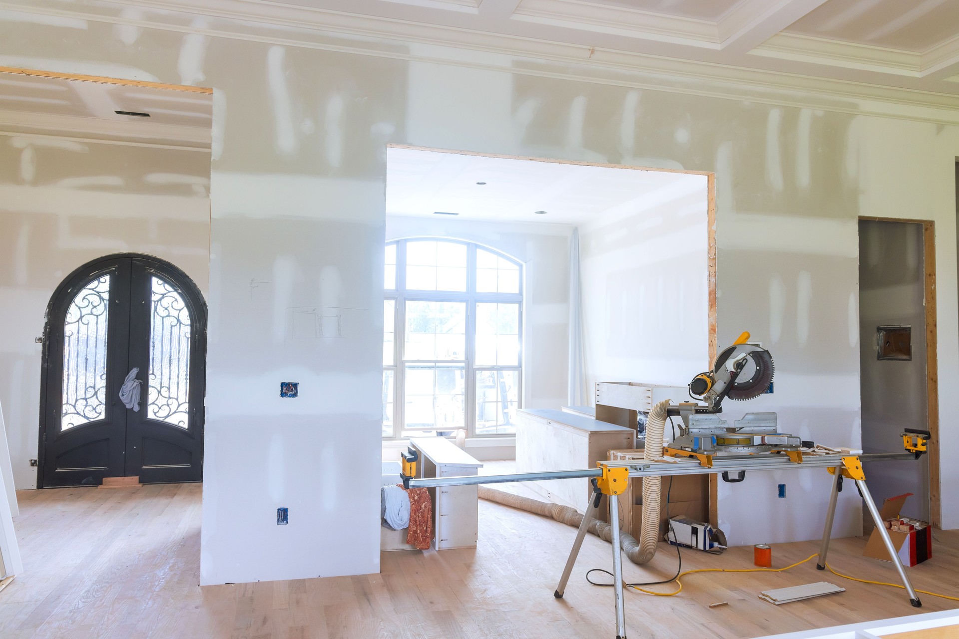 Construction progress showing partially finished interior with tools new doorway in home renovation project
